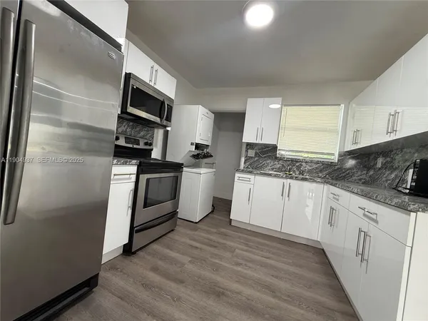 a kitchen with granite countertop a refrigerator stove and sink