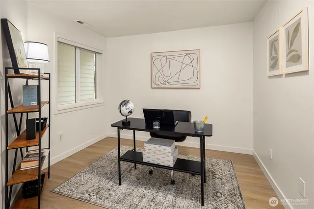 a view of a workspace room with wooden floor and windows