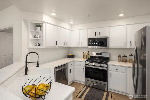a kitchen with stainless steel appliances a stove a sink a refrigerator and cabinets