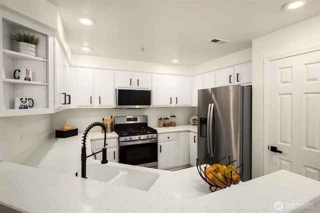a kitchen with stainless steel appliances kitchen island granite countertop a refrigerator and a stove top oven