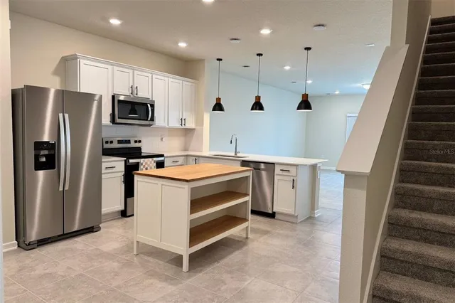 a kitchen with a sink stainless steel appliances and white cabinets