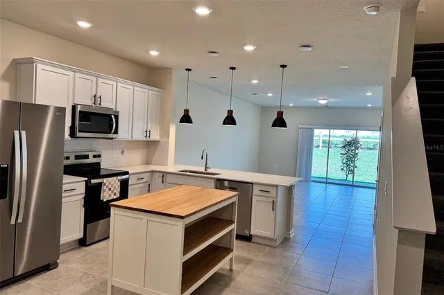 a kitchen that has a sink a stove top oven a refrigerator and a dishwasher with wooden floor