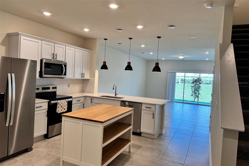 2759 Fetching Trail Davenport, FL 33896 - Photo 3 of 14 a kitchen that has a sink a stove top oven a refrigerator and a dishwasher with wooden floor