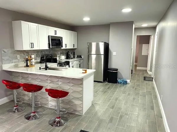 a kitchen with stainless steel appliances granite countertop a dining table chairs and granite counter tops