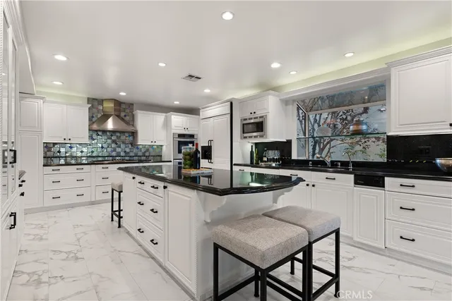 a kitchen with stainless steel appliances kitchen island granite countertop a stove a sink a refrigerator and a dining table with the kitchen view