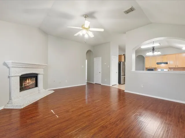 a view of an empty room with wooden floor and a fireplace