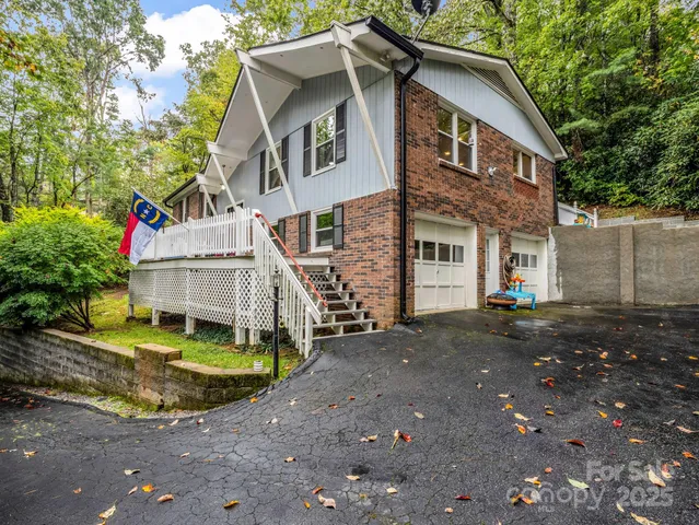 a view of a house with a yard and large tree