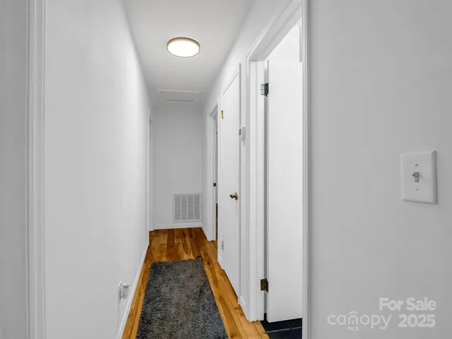 a view of a hallway with wooden floor and staircase