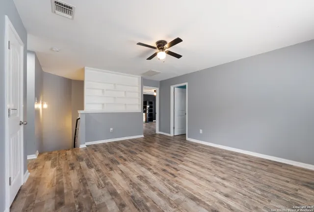 a view of an empty room with window and chandelier fan