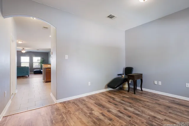 a view of a hallway with wooden floor and a bathroom