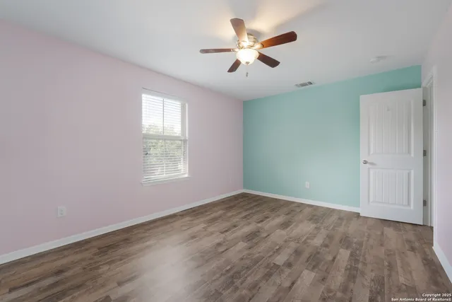an empty room with wooden floor and a ceiling fan