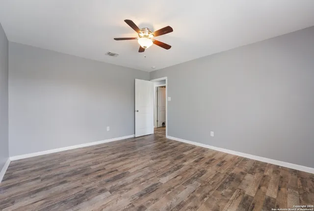 a view of a backyard with wooden fence and a large tree