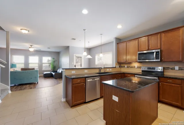 a kitchen with stainless steel appliances granite countertop a sink a stove and a microwave