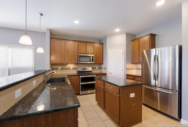 a kitchen with stainless steel appliances granite countertop a refrigerator a stove top oven a sink and dishwasher