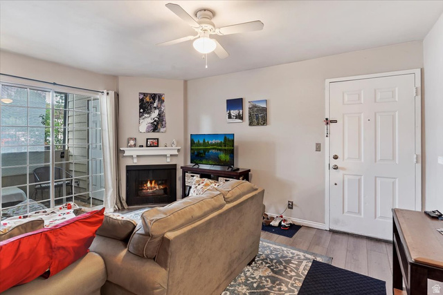 650 South Main Street, Unit 4104 Bountiful, UT 84010 - Photo 3 of 22 Living room featuring a ceiling fan, light wood-style flooring, and a lit fireplace