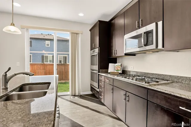 a kitchen with stainless steel appliances granite countertop a stove a sink and a microwave