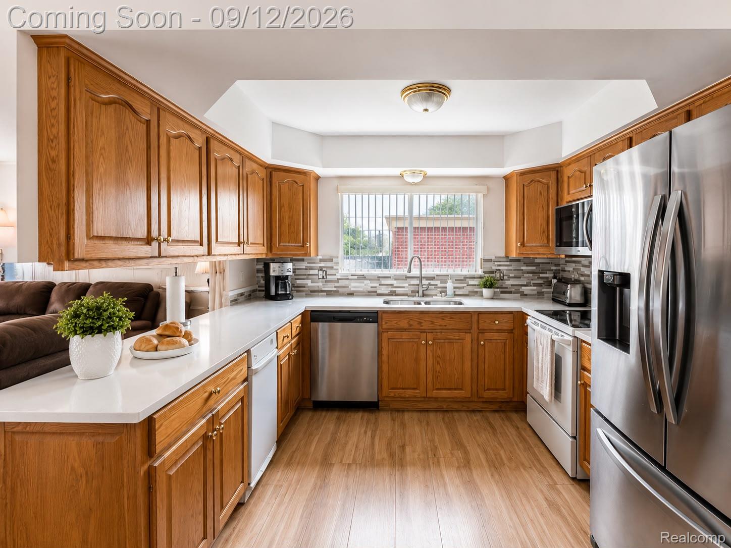 34398 Greentrees Road Sterling Heights, MI 48312 - Photo 7 of 36 Kitchen featuring wood-finish cabinetry, light countertops, wood-finish flooring, a mosaic tile backsplash, and stainless steel appliances