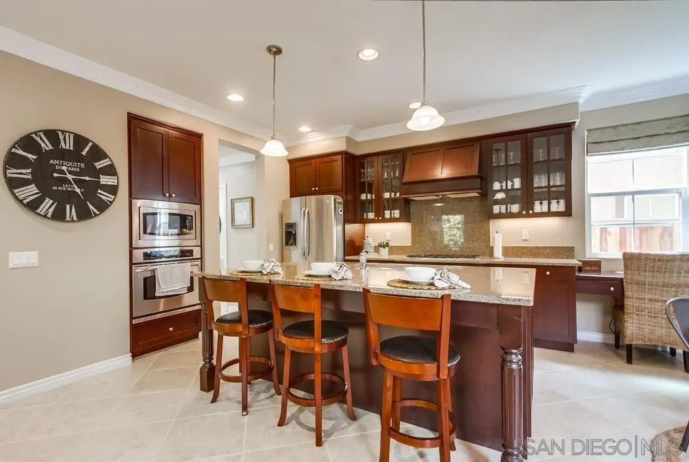 2665 Paradise Road Carlsbad, CA 92009 - Photo 11 of 52 a kitchen with stainless steel appliances kitchen island granite countertop a table chairs and a refrigerator