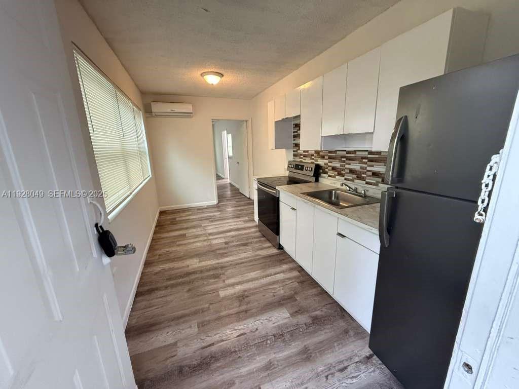 812 Northwest 26th Avenue, Unit B Miami, FL 33125 - Photo 4 of 8 a kitchen with a sink a refrigerator a stove top oven and cabinets