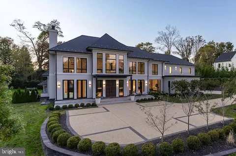 a view of a white house with a yard plants and large tree