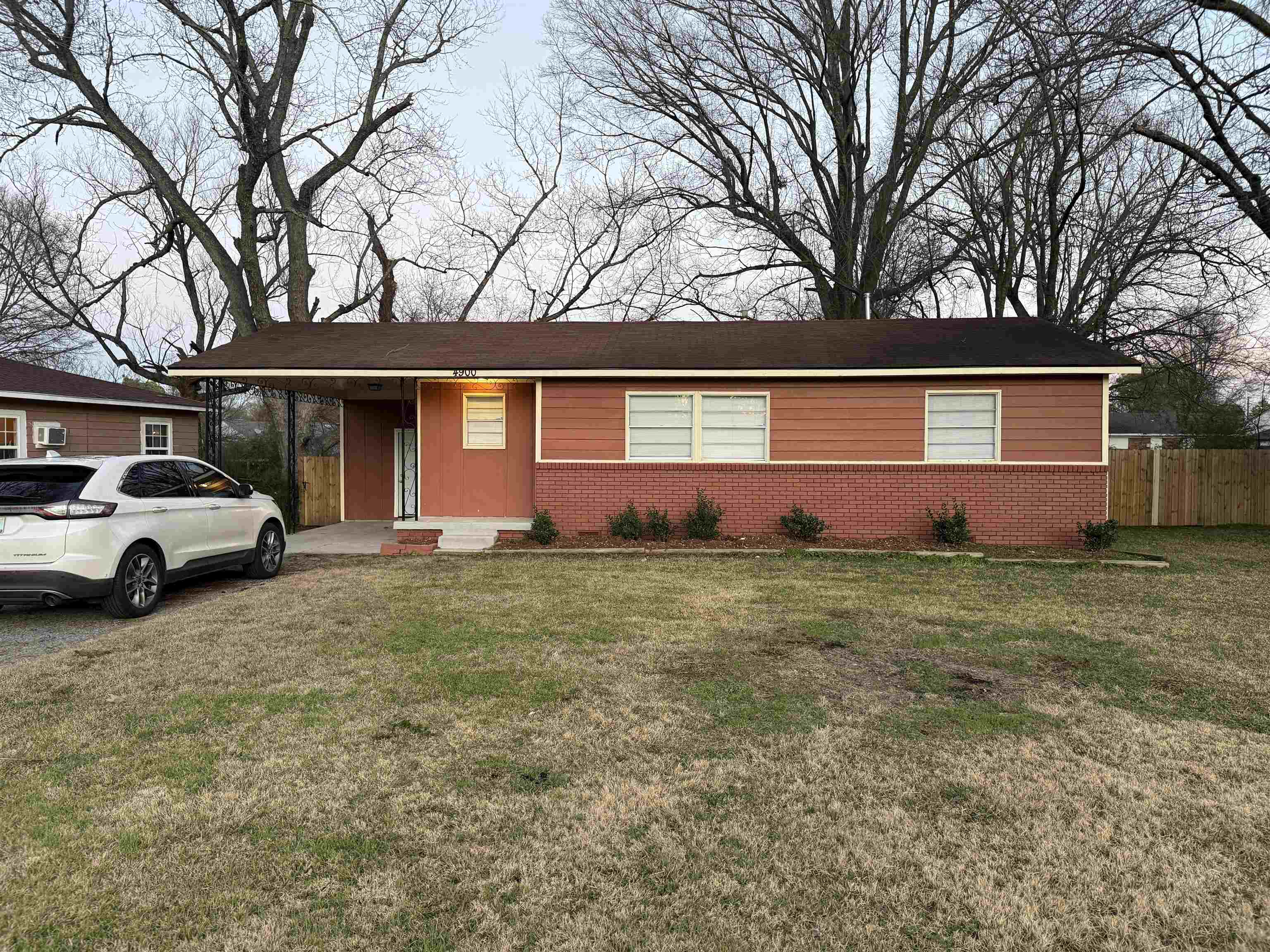 Ranch-style house with a porch, brick siding, and an attached carport