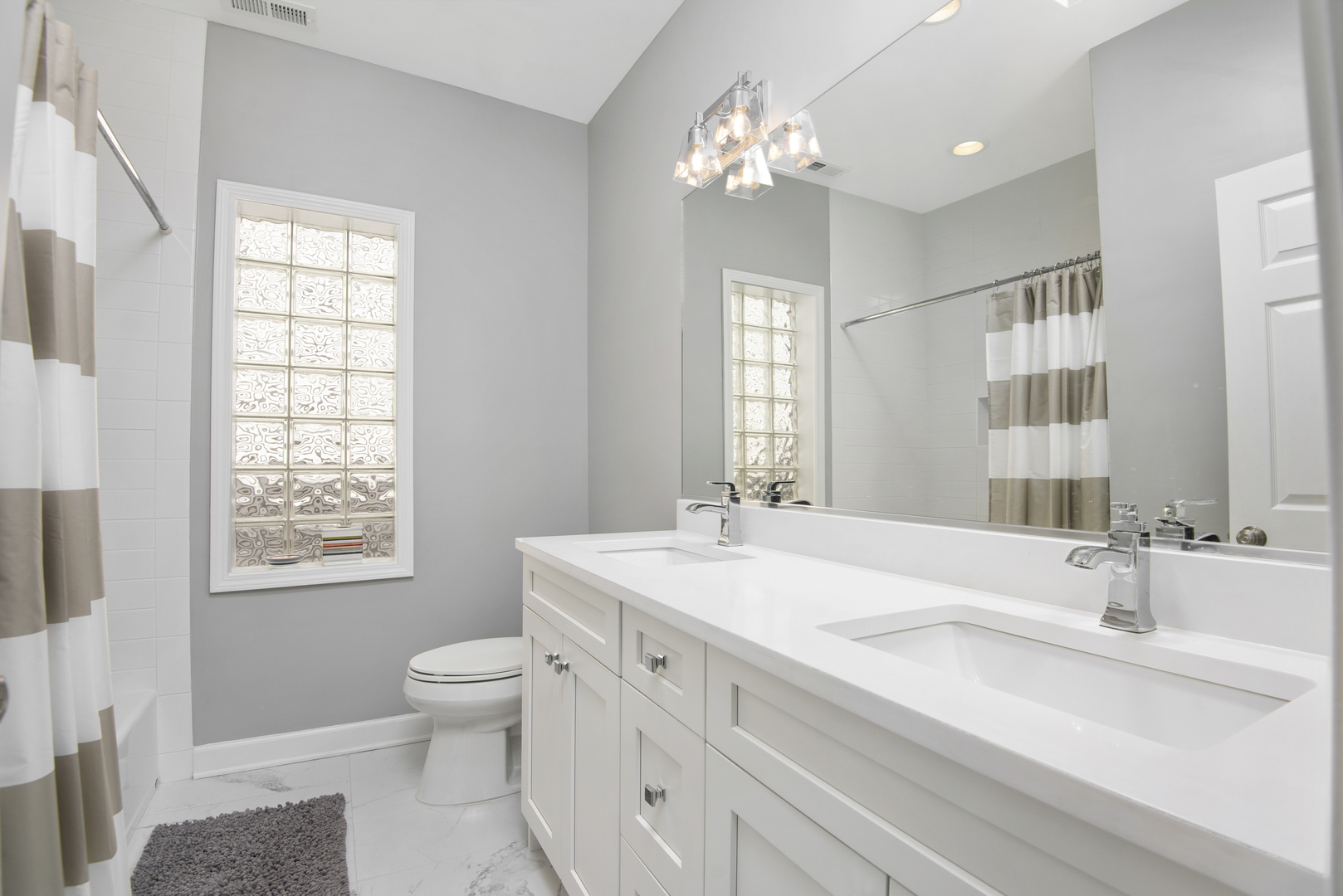 2918 North Racine Avenue Chicago, IL 60657 - Photo 17 of 26 a spacious bathroom with double vanity a toilet a mirror a window and vanity