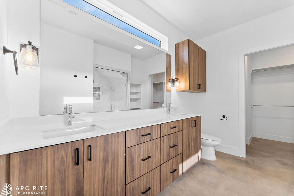 4509 22nd Place Lubbock, TX 79407 - Photo 14 of 32 a bathroom with a double vanity sink a toilet and a mirror