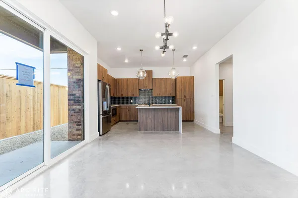 a large kitchen with kitchen island a large counter top stainless steel appliances and cabinets