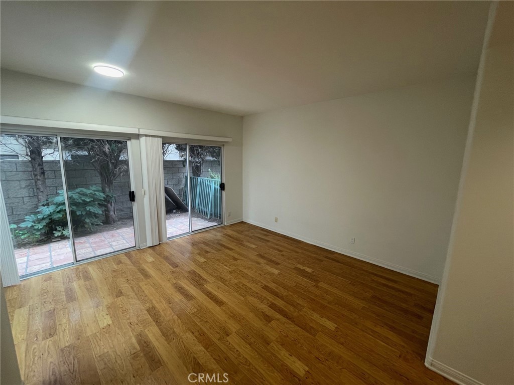 10010 Reseda Boulevard, Unit D Northridge, CA 91324 - Photo 8 of 22 a view of an empty room with wooden floor and a floor to ceiling window