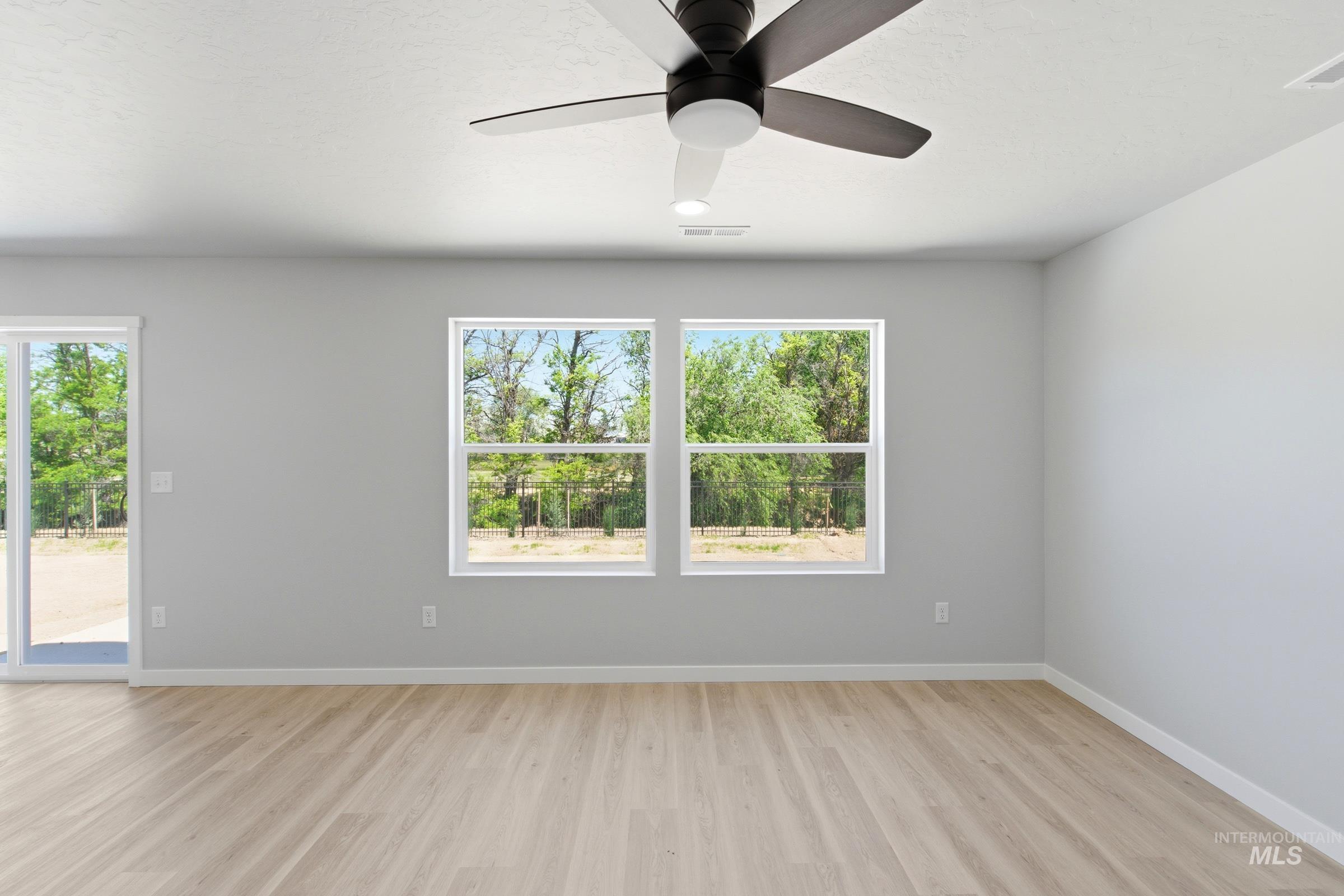 2374 West Fallon Loop Nampa, ID 83651 - Photo 11 of 24 Spacious room featuring light wood-finish flooring, a modern ceiling fan, and two large windows providing natural light