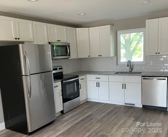 a kitchen with granite countertop white cabinets and stainless steel appliances