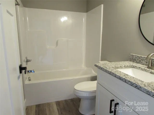 a bathroom with a granite countertop bathtub sink vanity mirror and toilet