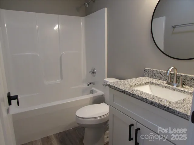a bathroom with a granite countertop toilet a sink and a mirror