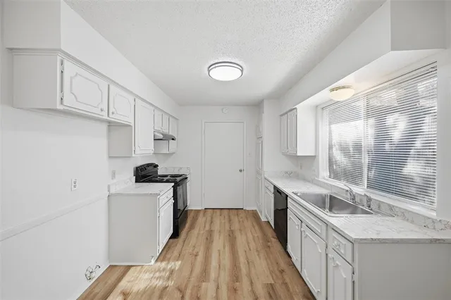 a kitchen with granite countertop a sink a counter space cabinets and stainless steel appliances
