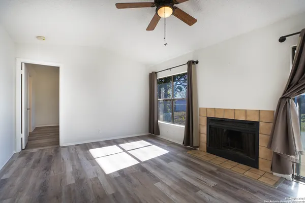 an empty room with wooden floor a fireplace and windows