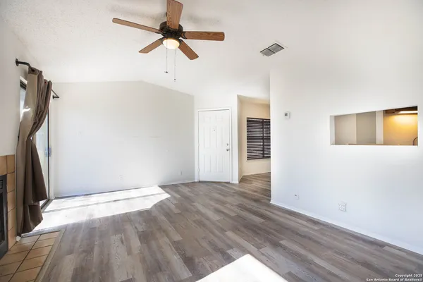 a view of empty room with wooden floor and fan