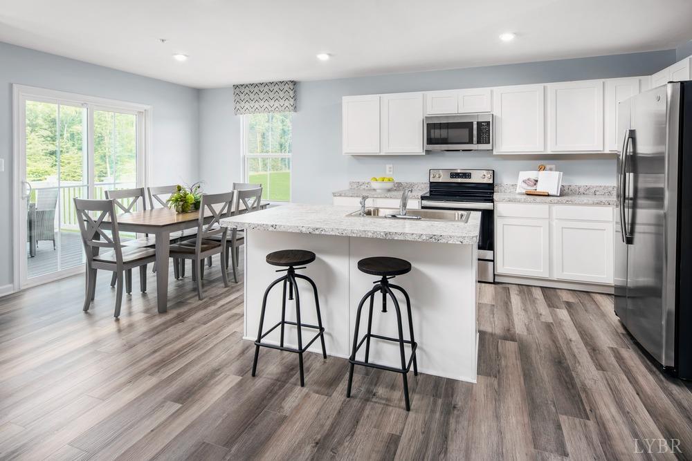 236 Thicket Drive Lynchburg, VA 24501 - Photo 3 of 16 a kitchen with microwave a stove a sink and white cabinets with wooden floor