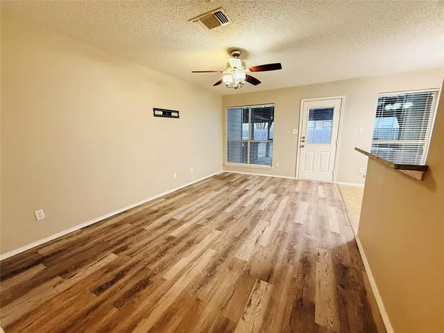 a view of empty room with wooden floor and fan