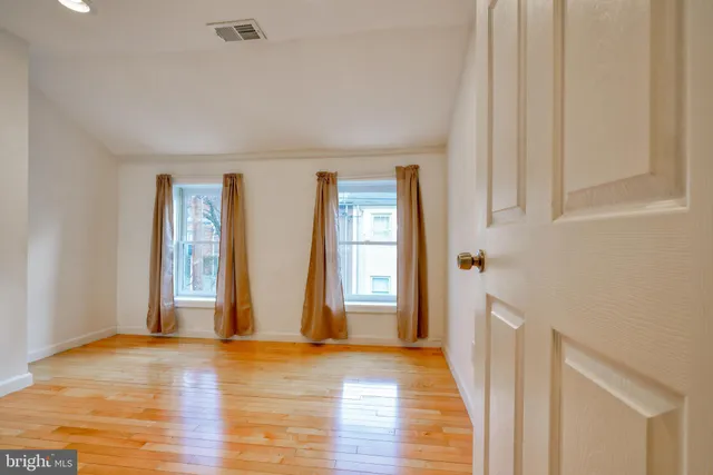 a view of an empty room with wooden floor and windows