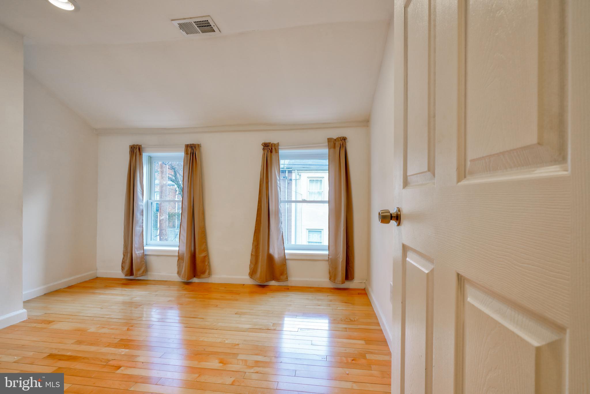 1029 Booth Street Baltimore, MD 21223 - Photo 11 of 21 a view of an empty room with wooden floor and windows