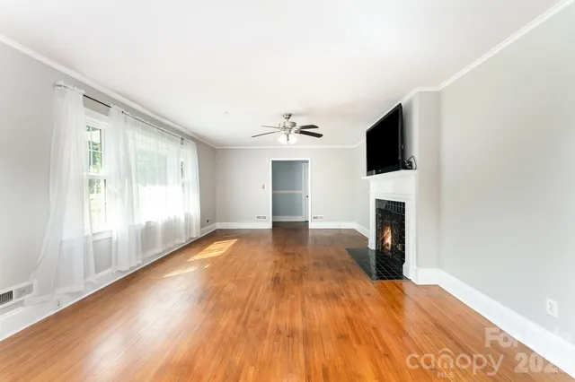 a view of empty room with a fireplace and wooden floor