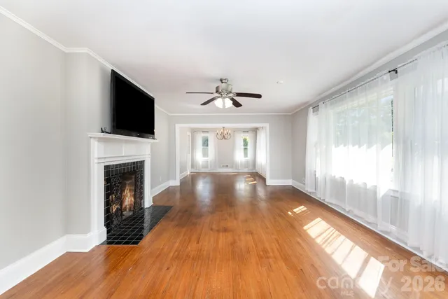 a view of an empty room with wooden floor fireplace and a window