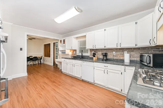 a kitchen with stainless steel appliances granite countertop a stove a sink dishwasher and a microwave oven with white cabinets