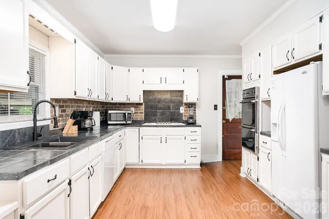 a kitchen with granite countertop a refrigerator stove top oven and sink
