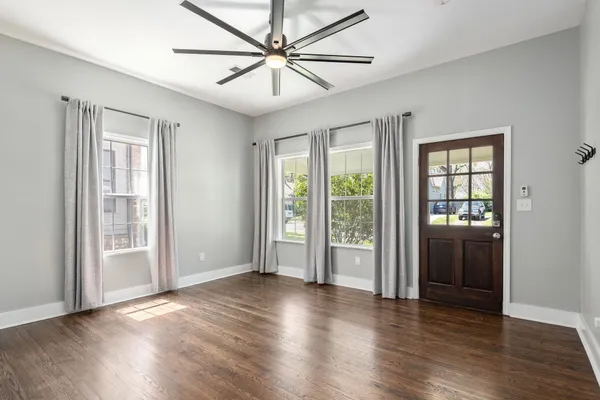 a view of an empty room with wooden floor and a window