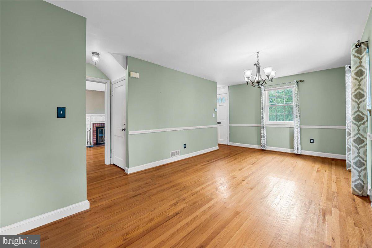 10101 Portland Road Silver Spring, MD 20901 - Photo 7 of 33 an empty room with wooden floor and chandelier