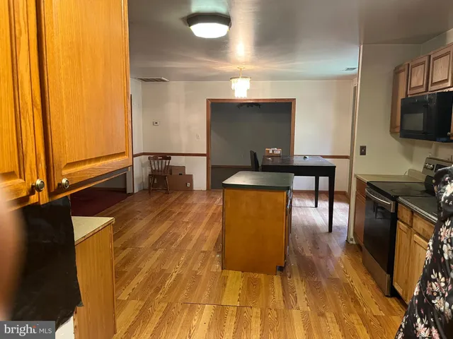 a view of a kitchen with kitchen island a sink wooden floor and a counter top space