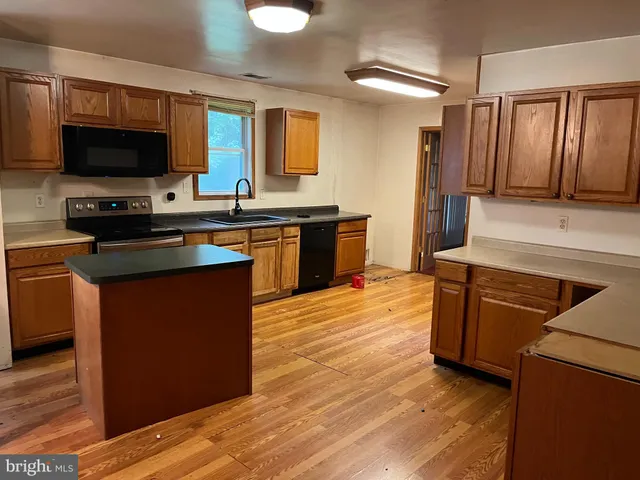 a kitchen with stainless steel appliances kitchen island granite countertop a stove a sink and a microwave