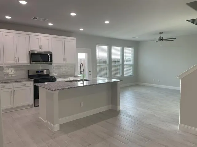 a kitchen with stainless steel appliances granite countertop a stove a sink and a microwave