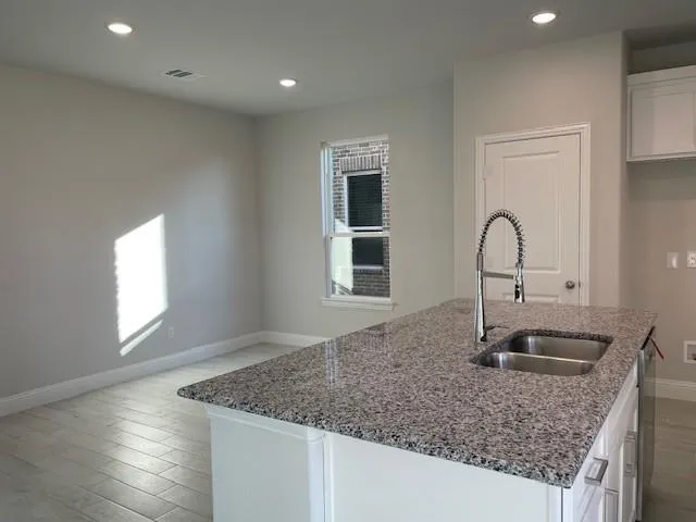 a kitchen with stainless steel appliances kitchen island granite countertop a refrigerator and a sink